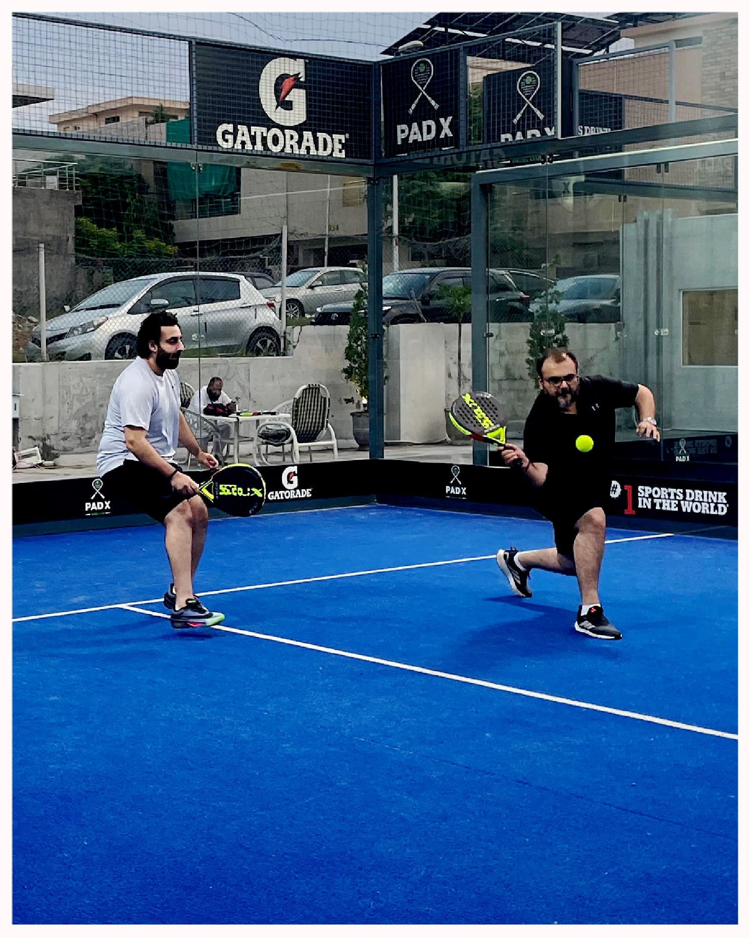 Two ZRK Group colleagues playing padel on a blue court
